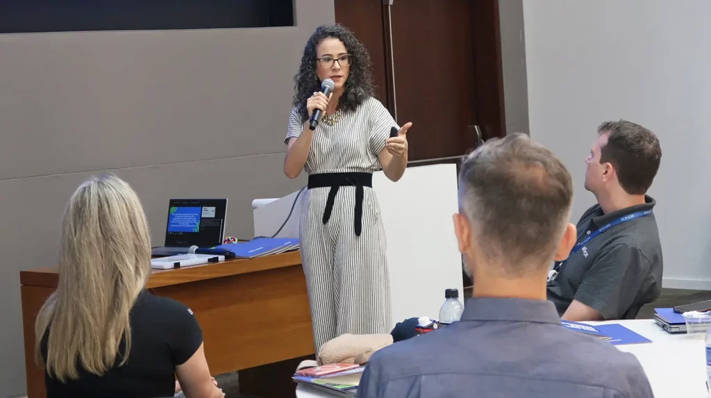 Mulher palestrando para colaboradores de uma empresa. Add reaction