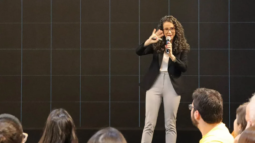 mulher falando no microfone apresentando  palestra corporativa