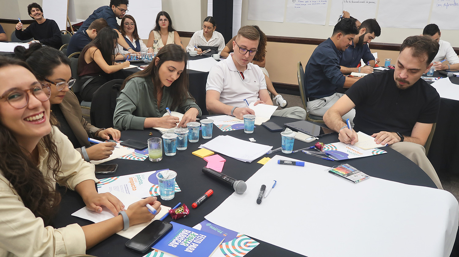Trainees da Aegea reunidos em pequenos grupos durante exercício de narrativa corporativa.